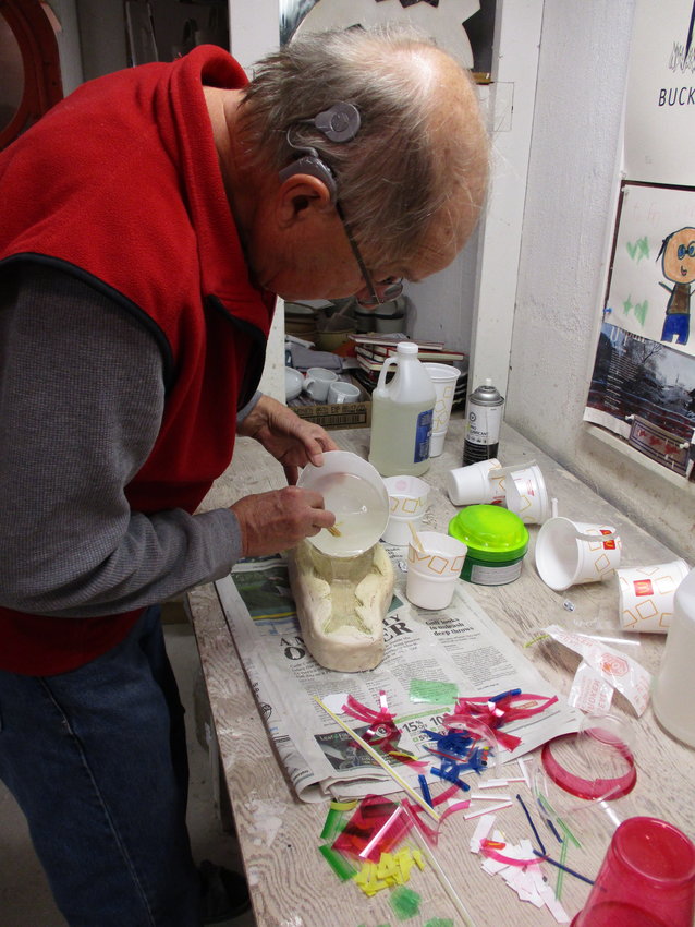 Craig Hinshaw pours viscous resin into a mold to create “Rainbow Trout.” 